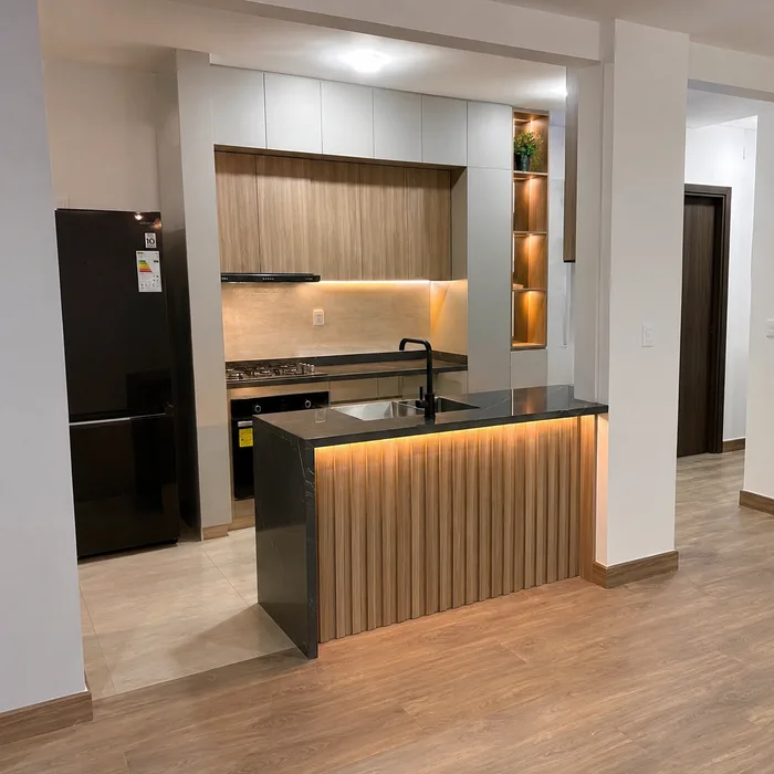 Cocina integral moderna en Bucaramanga con isla negra, muebles en tonos madera y accesorios en dorado
