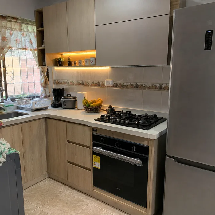 Cocina integral moderna en Bucaramanga con gabinetes de madera clara y encimera blanca