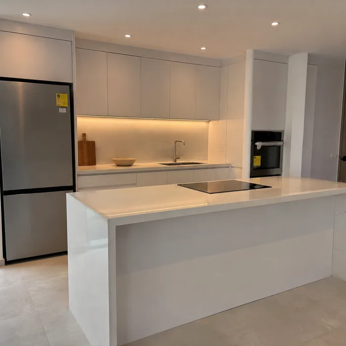 Cocina integral moderna blanca con isla, encimera beige y electrodomésticos en Bucaramanga