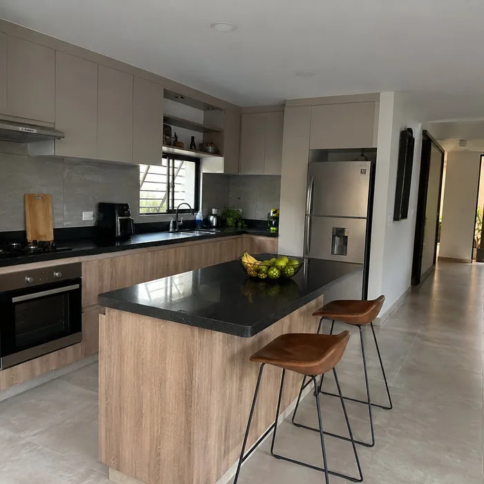 Cocina integral moderna en Bucaramanga con isla de madera, encimera negra y taburetes de cuero