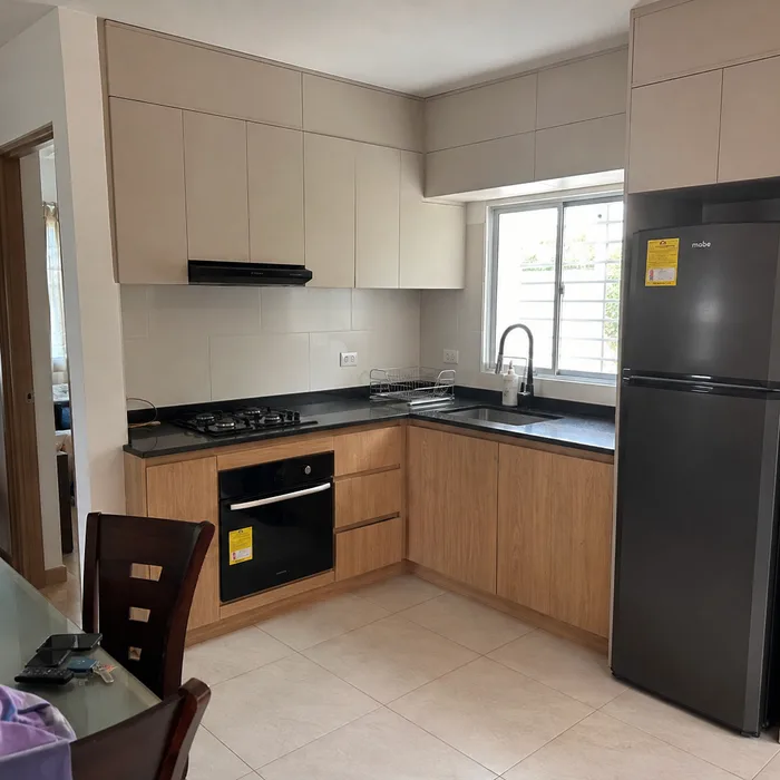 Cocina integral moderna en Bucaramanga con gabinetes blancos, frentes en madera y encimera negra