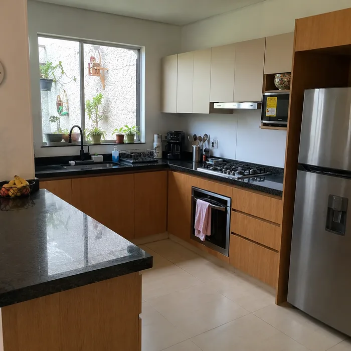 Cocina integral en madera y blanco con encimera negra instalada en Bucaramanga