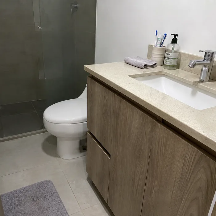 Baño moderno en Bucaramanga con vanitory de madera clara y espejo gris oscuro