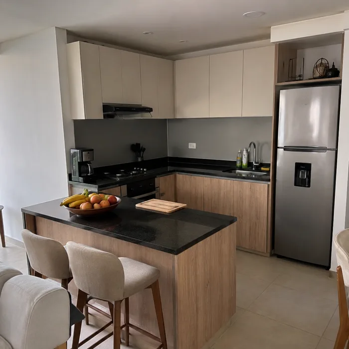 Cocina integral moderna en Bucaramanga con gabinetes blancos, madera natural y encimera negra