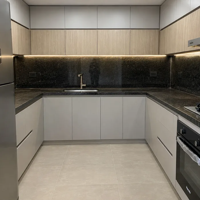 Cocina integral moderna con gabinetes blancos y encimera negra en Bucaramanga