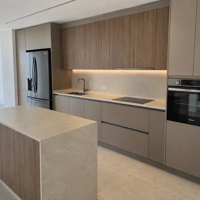 Cocina integral moderna con gabinetes en tonos naturales y encimera gris en Bucaramanga